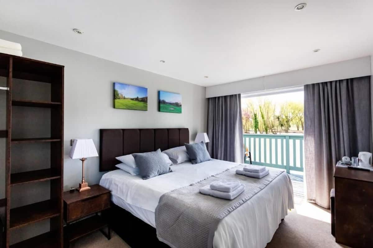 A bedroom with a bed, a nightstand, a wardrobe, and a balcony with curtains.