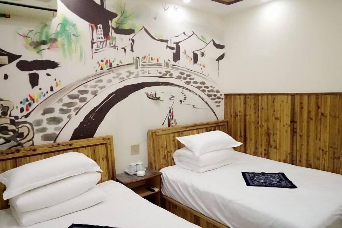 Habitació amb dos llits, ambres a la fusta, un mural a la paret i panells de fusta al mur.