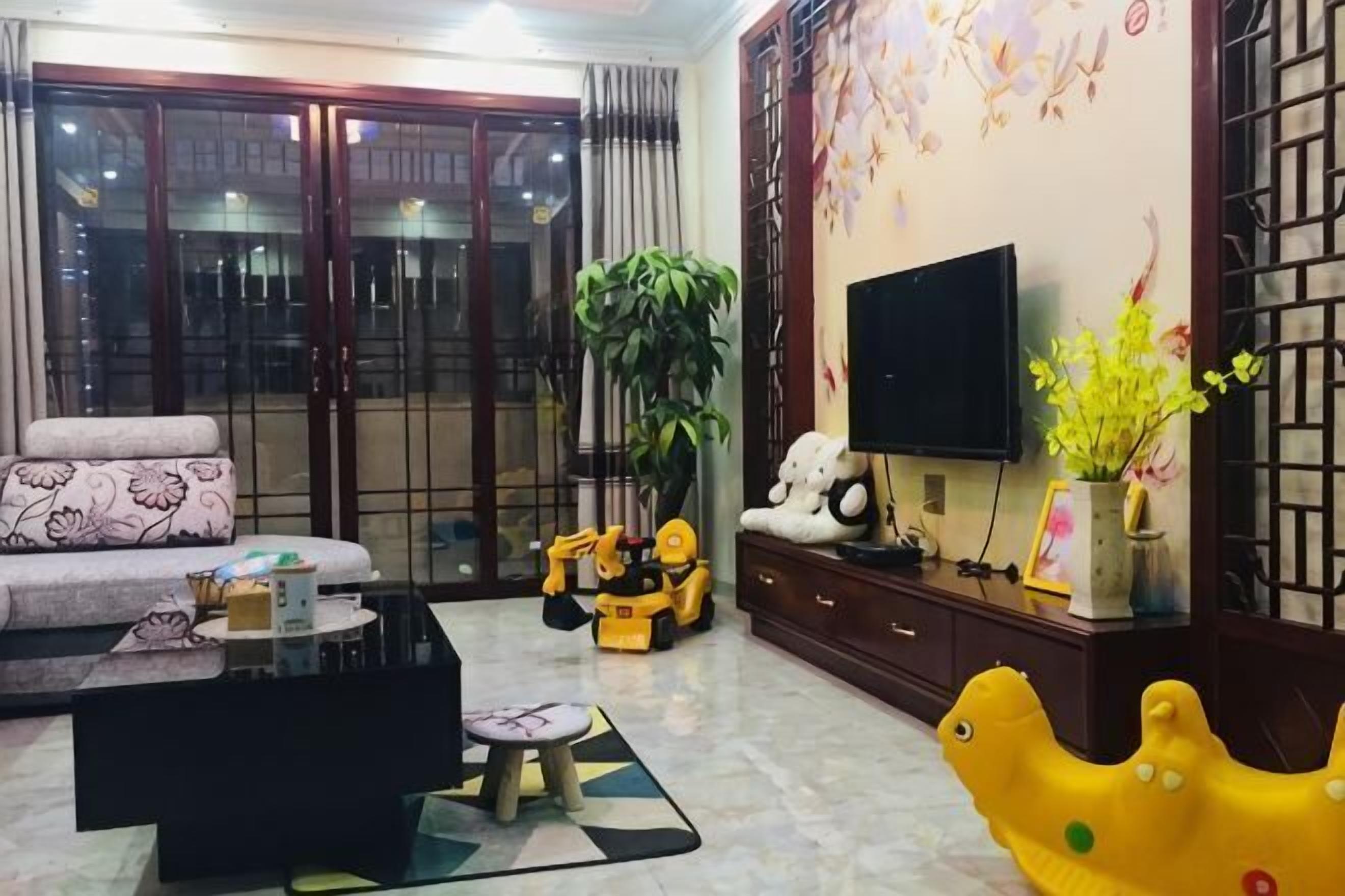 Sala de estar com sofá, mesa de centro, televisão e objetos decorativos.
