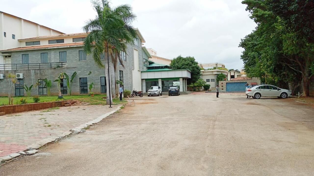 A building with a paved driveway, parked cars, and a palm tree.