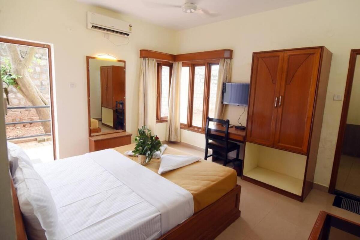 Une chambre à coucher comprenant un lit, un bureau, une chaise, une armoire et un téléviseur.
