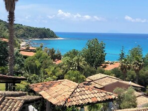 A coastal view with terracotta-roofed buildings, lush greenery, and a clear blue sea. - Villetta sul mare (Parghelia)