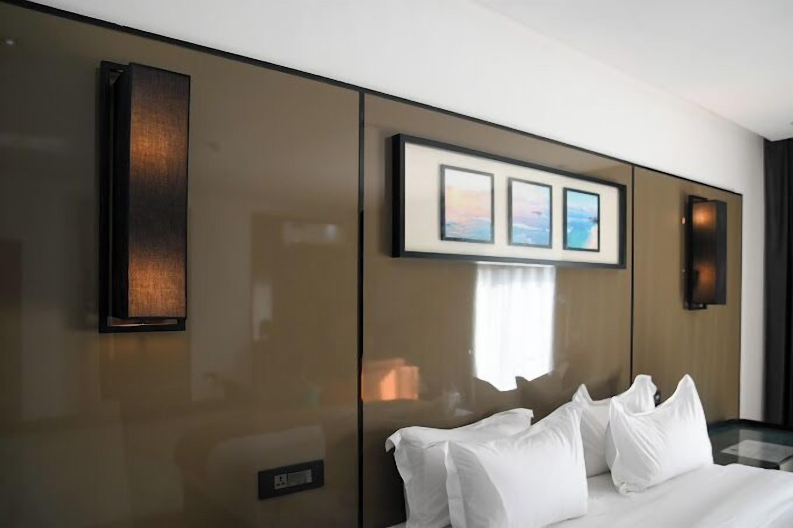 Una habitación de hotel con una cama grande, una obra de arte colgada en la pared y un panel de control.