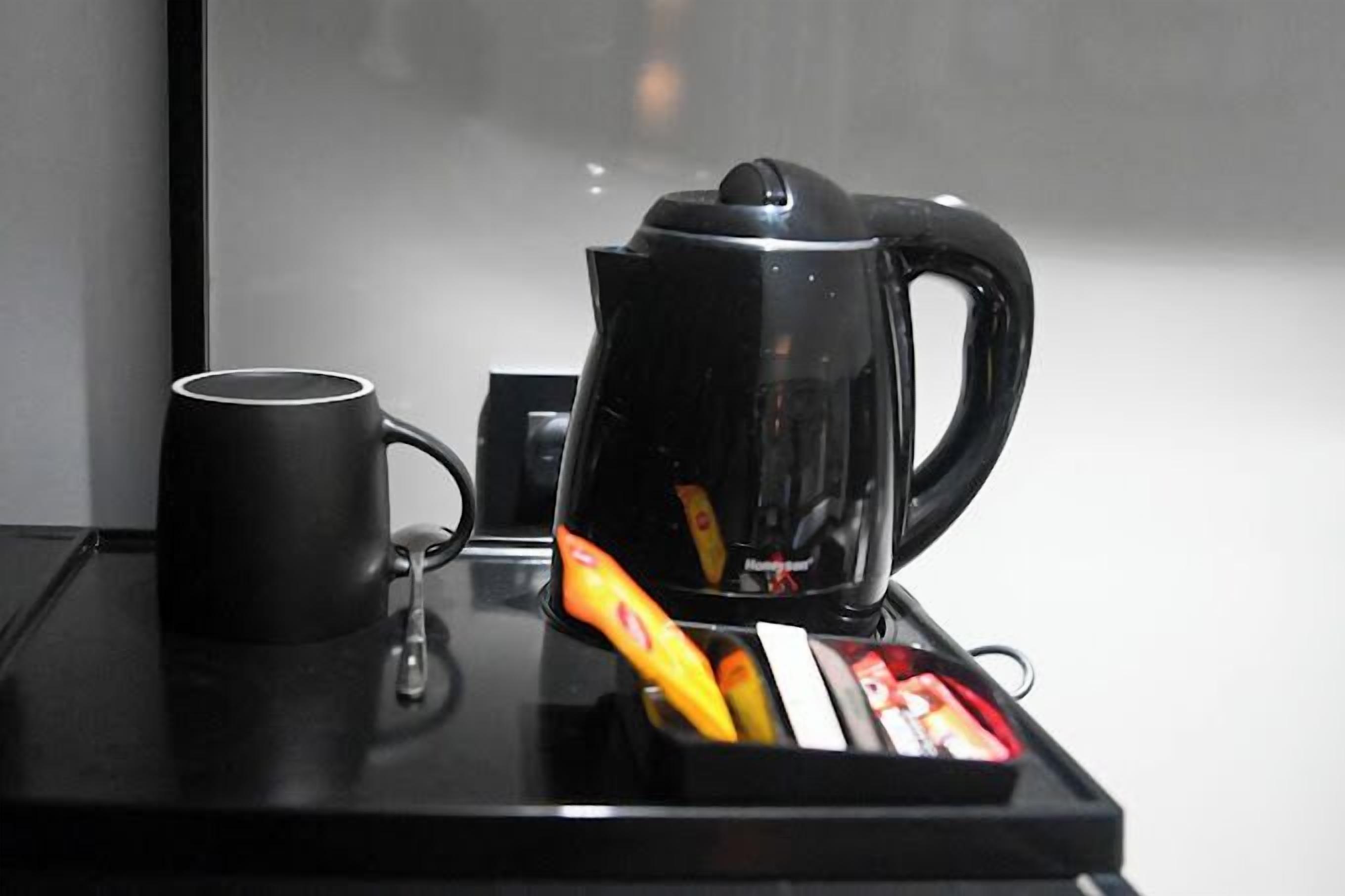 Une machine à café noire et une tasse noire sur un plateau noir.