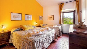 A hotel room with two beds, a window with curtains, a small table with a teapot, and framed pictures on the wall. - Villa Pietraia (Certaldo)