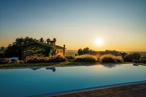 Ein Schwimmbecken mit freiem Blick auf ein Haus und umliegendes Grün.