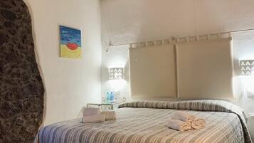 Une chambre à coucher avec un lit, un mur en pierre, un tableau et une fenêtre.