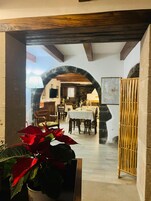 Vista interior de un comedor con un arco de piedra, vigas de madera y una mesa dispuesta para comer.