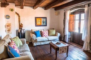 Una sala de estar acogedora con techo de madera, un sofá, una mesa de centro y un cuadro en la pared.