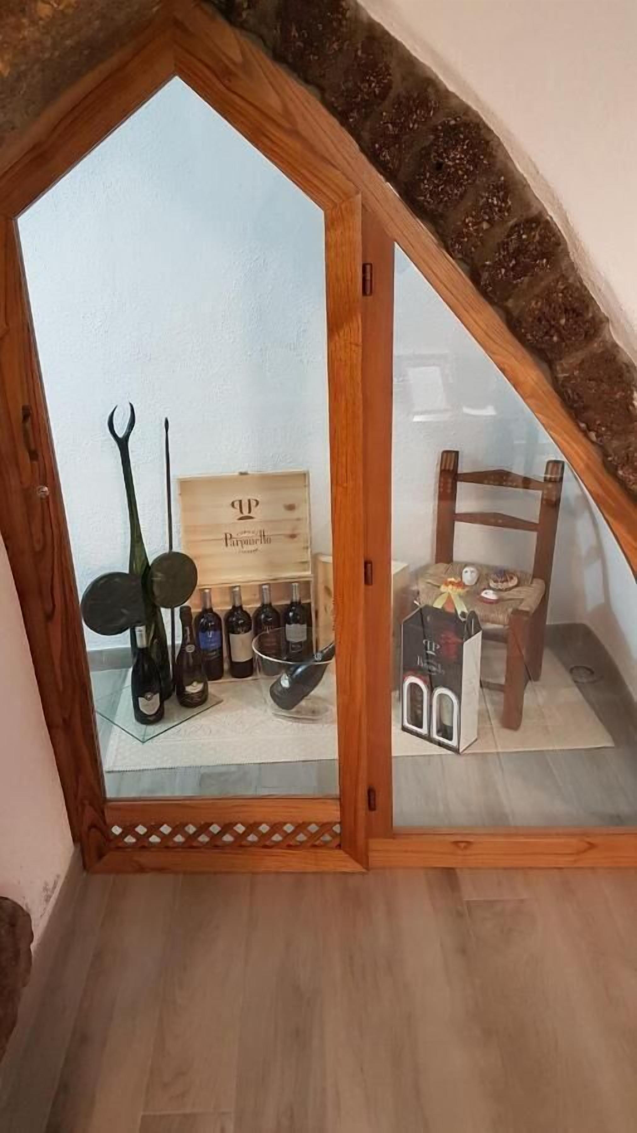 Una habitación pequeña y acogedora con techo inclinado, una silla de madera, una mesa pequeña y un cofre de madera con la etiqueta “P&P”.