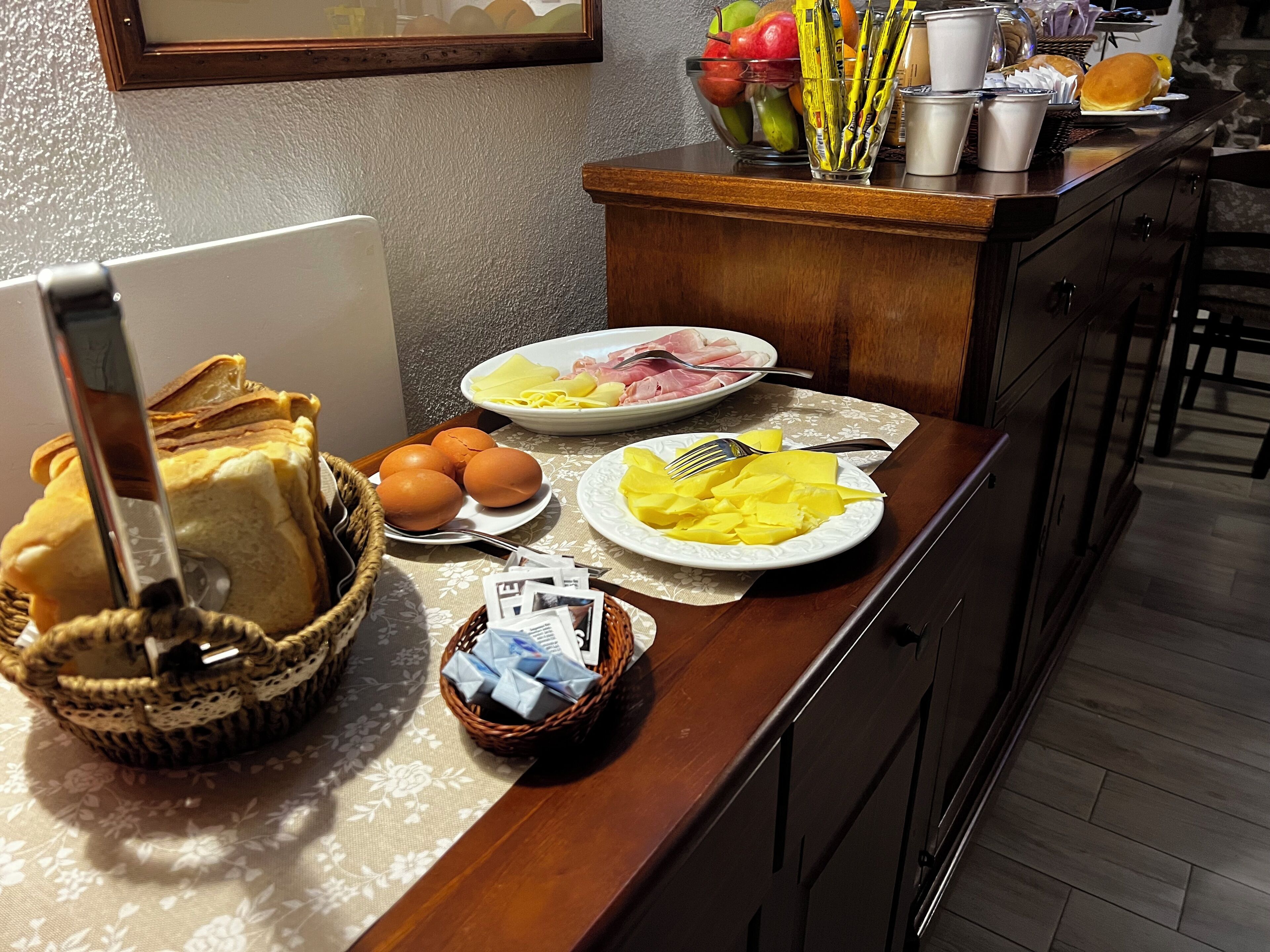 Un buffet de petit-déjeuner avec du pain, des œufs et des assiettes remplies de nourriture, le tout disposé sur un comptoir en bois.