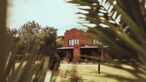 A building with a red facade, surrounded by greenery and trees. - Hacienda Altomonte (San Rafael)