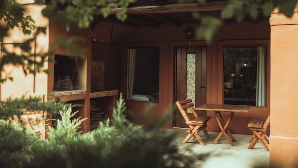An outdoor seating area with wooden furniture, a wooden table, and chairs, surrounded by greenery. - Hacienda Altomonte (San Rafael)