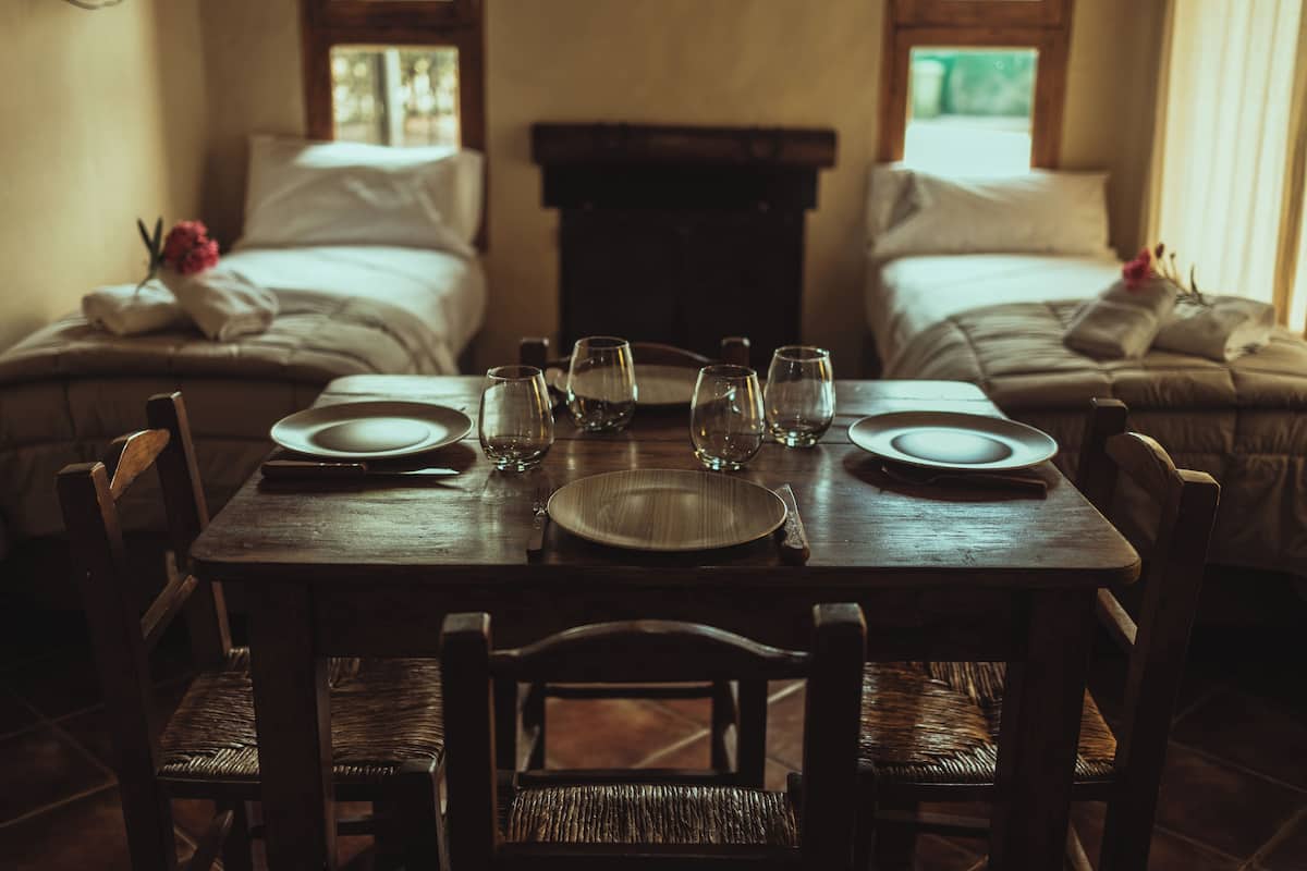 Una mesa de comedor dispuesta para dos personas, con platos, vasos y cubiertos.
