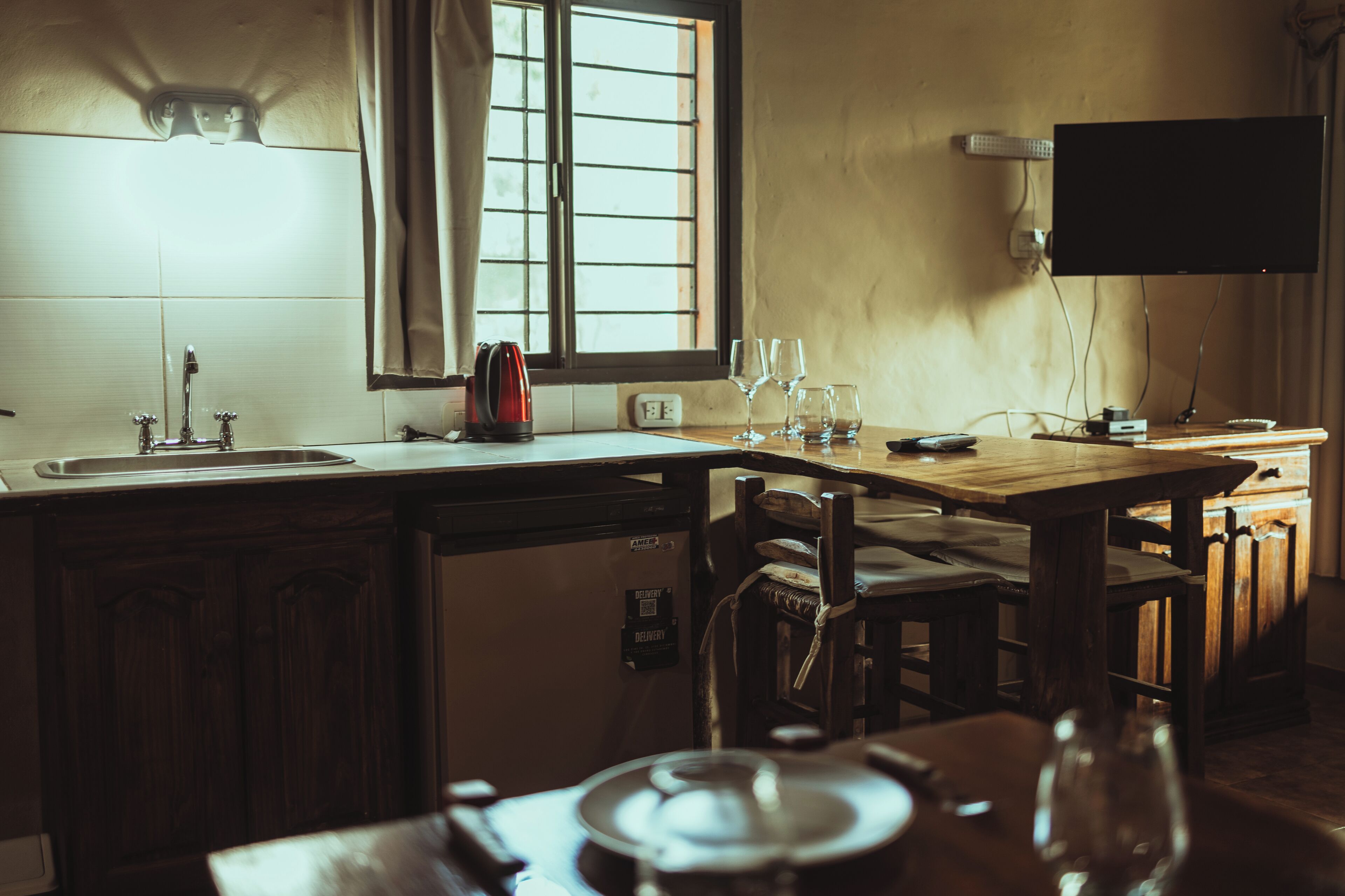 A kitchen with a window, a sink, a stove, and a dining table with chairs.