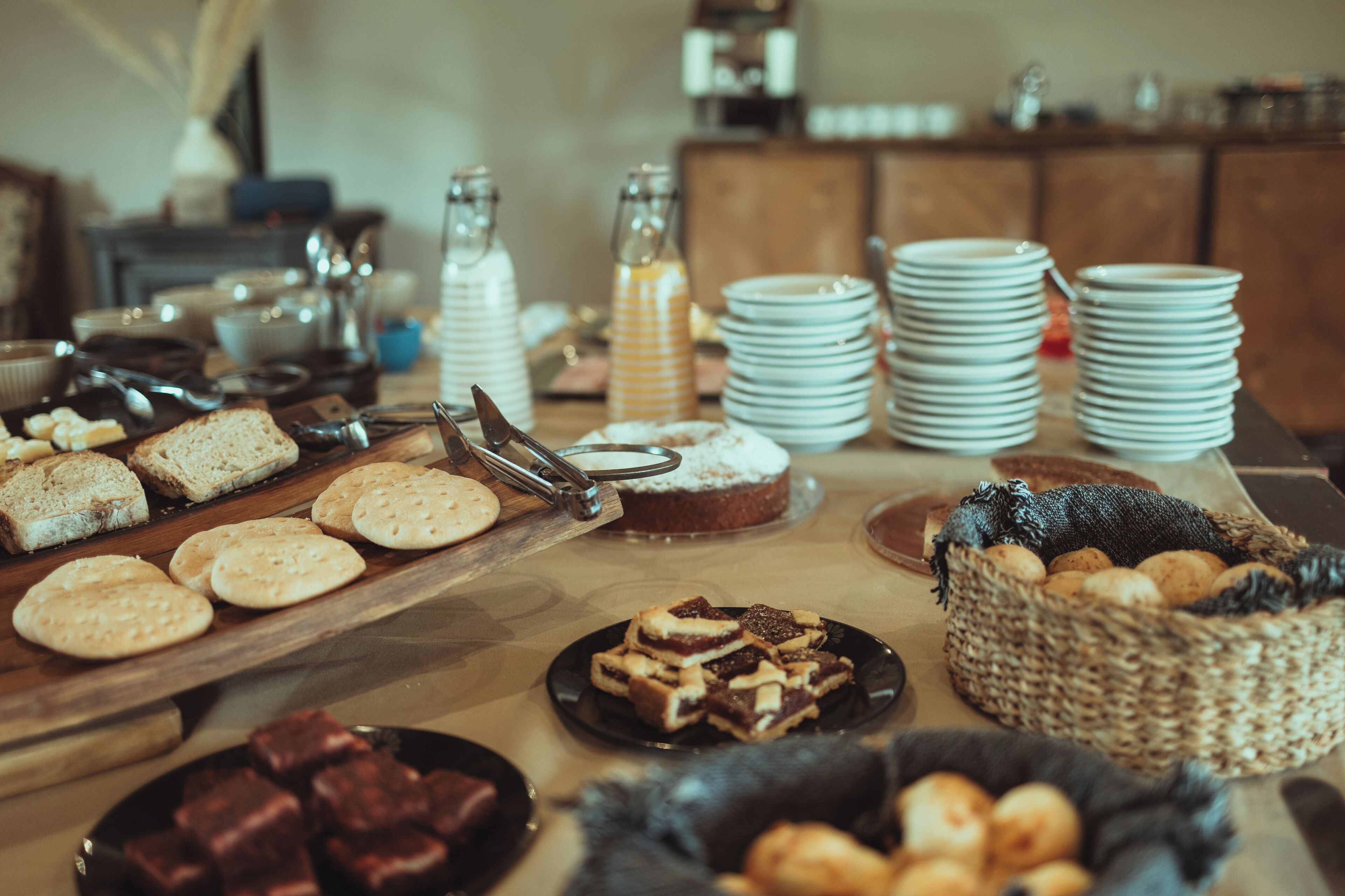 Una mesa de buffet con diversos alimentos, como pan, pasteles y postres, dispuesta sobre una mesa de madera.