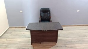 A conference room with a dark wooden table and a black leather chair. - VS Grand (Bara Banki)