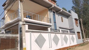 A two-story building with a balcony on the upper floor, a garage door, and a decorative wall pattern. - VS Grand (Bara Banki)