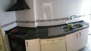 A kitchen with a black stove, a sink, and a dishwasher. - Sunny beach apartment in Las Palmeres/Valencia (Sueca/Les Palmeres)