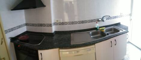 A kitchen with a black stove, a sink, and a dishwasher.