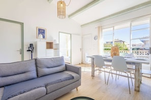 Uma sala de estar moderna com sofá, mesa de jantar, cadeiras e janelas amplas.