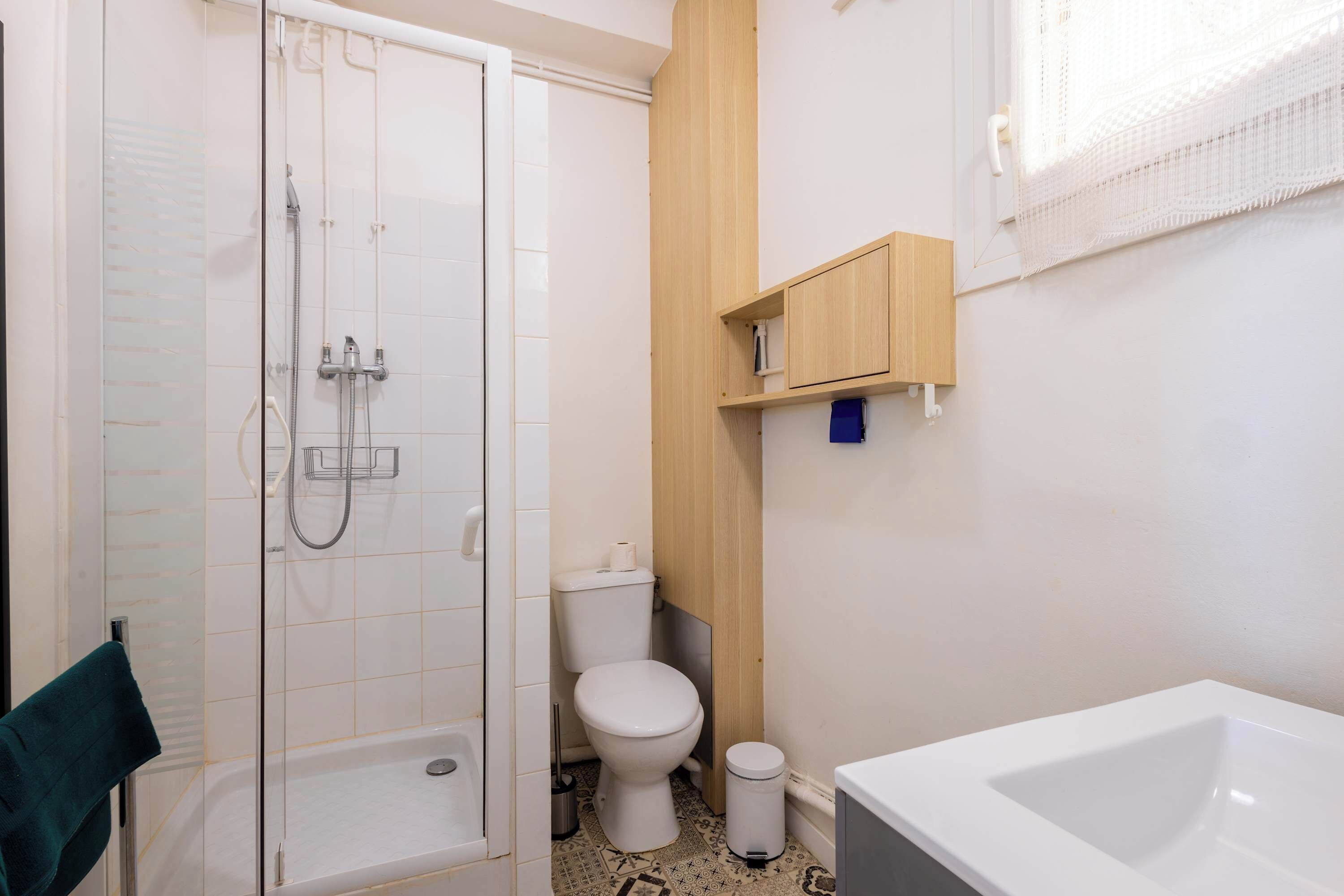 Ein Badezimmer mit Duschkabine aus Glas, Toilette, Waschbecken und einem Holzschrank.