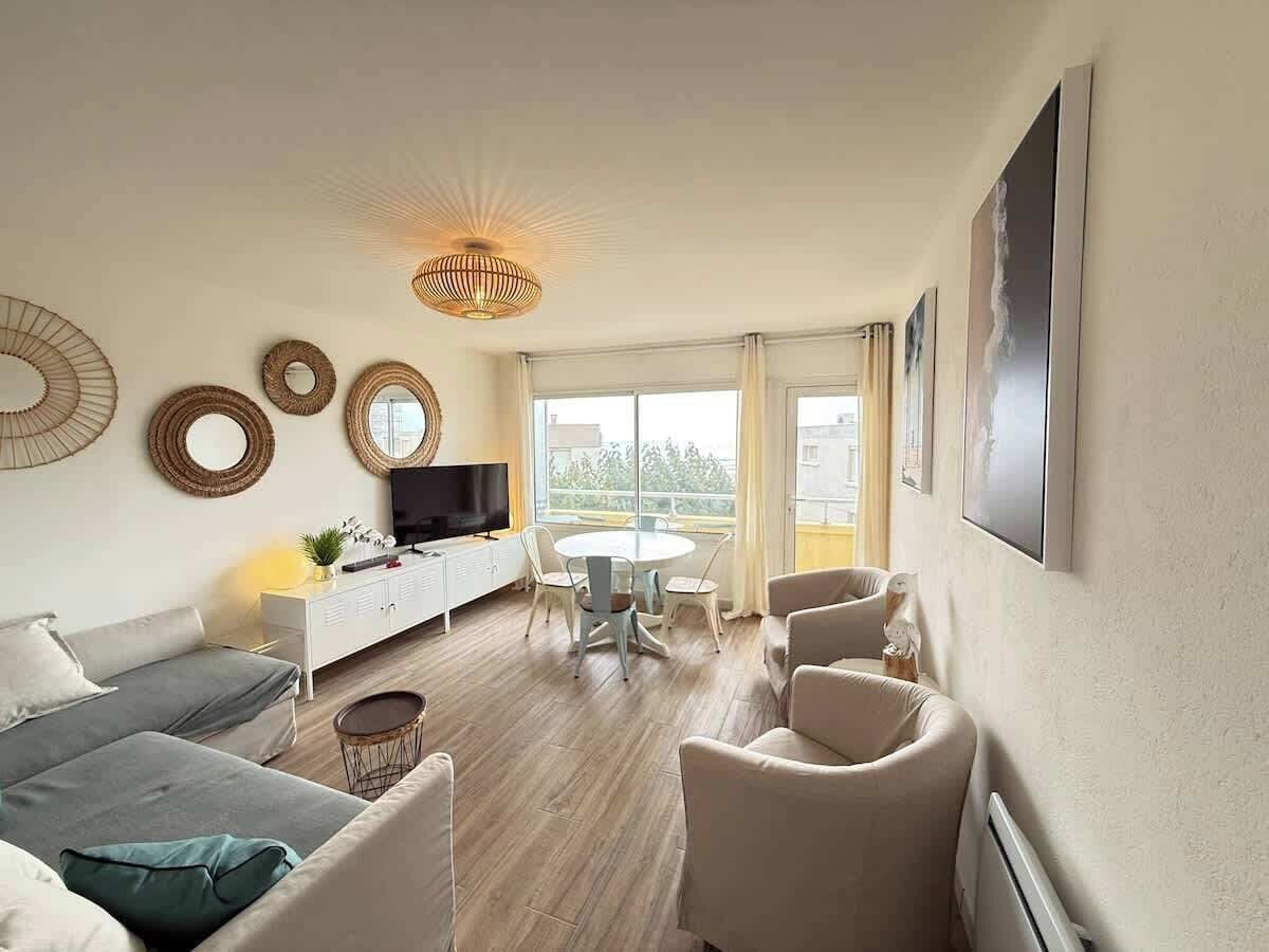 A modern living room with a sofa, chairs, a dining table, and a TV.