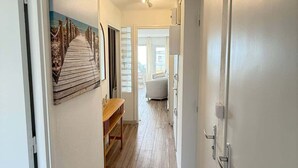 A hallway with wooden flooring, a bench, and a painting of a beach scene.