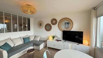 A modern living room with a sectional sofa, a dining table, and a television.