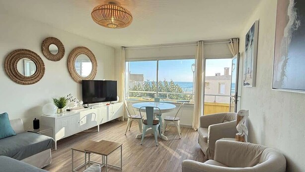 A modern living room with a TV, sofa, chairs, and a dining table.