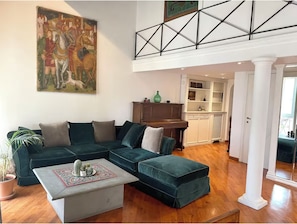A living room with a sectional sofa, a coffee table, and a painting on the wall.