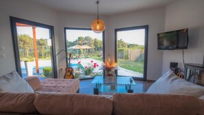 A modern living room with a glass coffee table, a pink sofa, and a guitar.