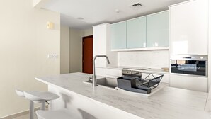 Una cocina moderna con encimera de mármol, pileta de acero inoxidable y armarios verde claro.