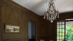 A room with a wooden floor, a sofa, a coffee table, and a chandelier. - `Villa du Parc`*Parking*Proche centre*Calme (Montauban)