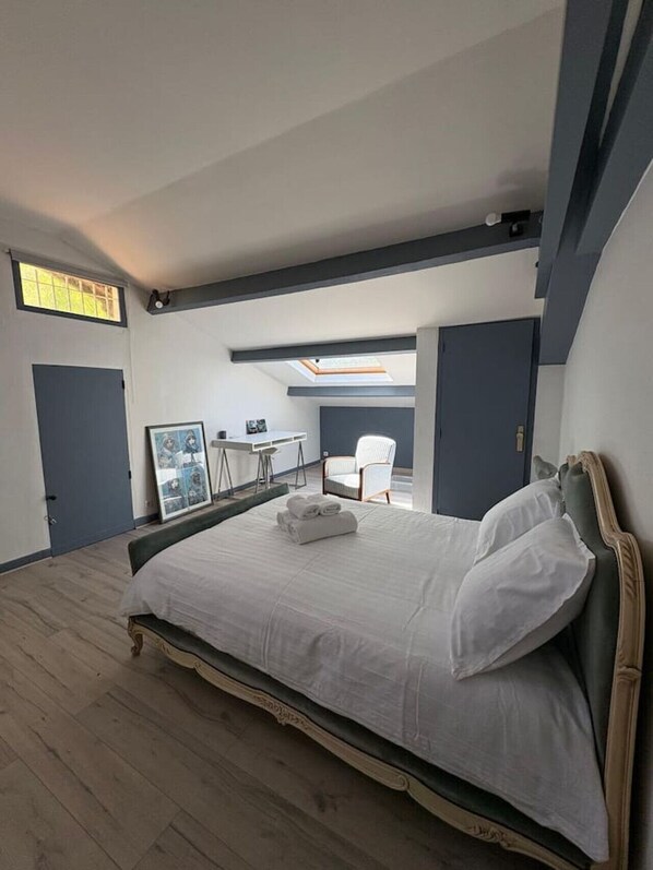 A bedroom with a large bed, a desk, and a chair.