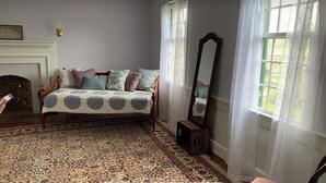 Un dormitorio con una cama, un espejo, una chimenea y un ventanal con cortinas.