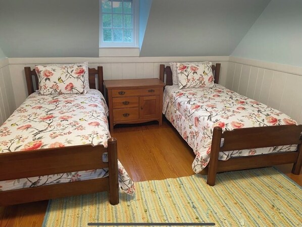 Un dormitorio con dos camas de madera, una mesita de noche y una ventana.