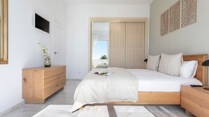 A modern bedroom with a large bed, wooden dresser, and a sliding closet door. - Genteel Home Royal Gardens Marbella (Marbella)