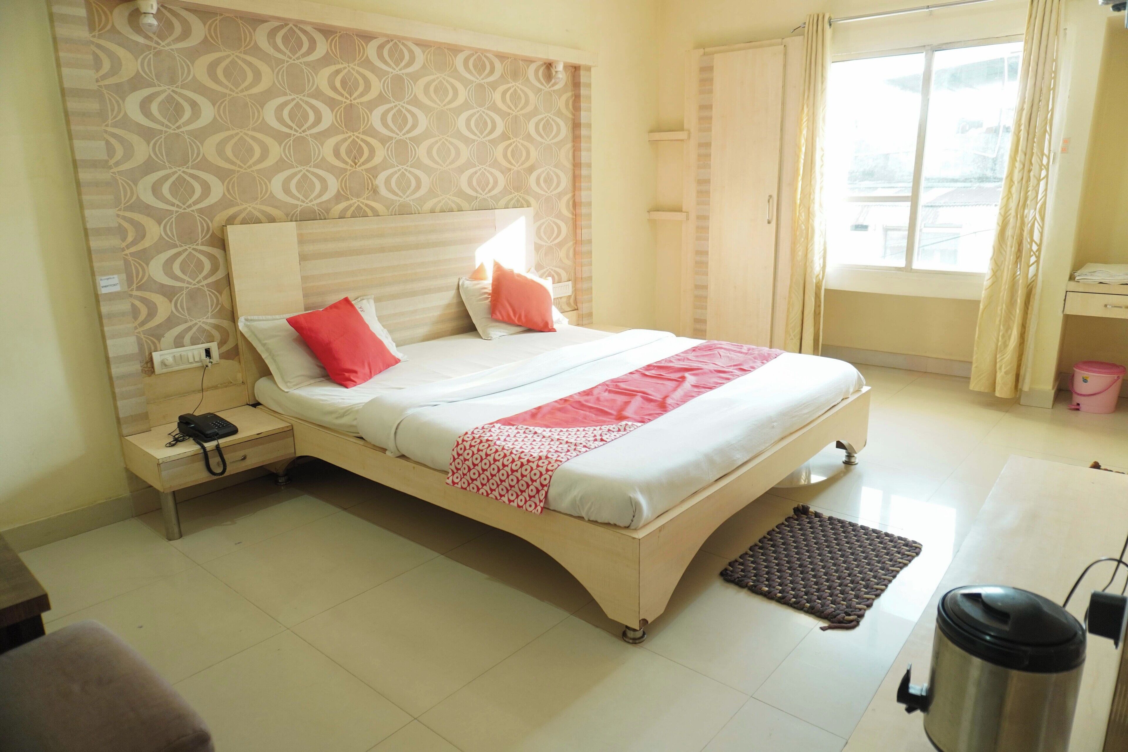 A neatly arranged hotel room with a bed, bedside table, and a window with curtains.