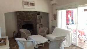 A cozy room with a stone fireplace, wicker furniture, and a view of the outside.