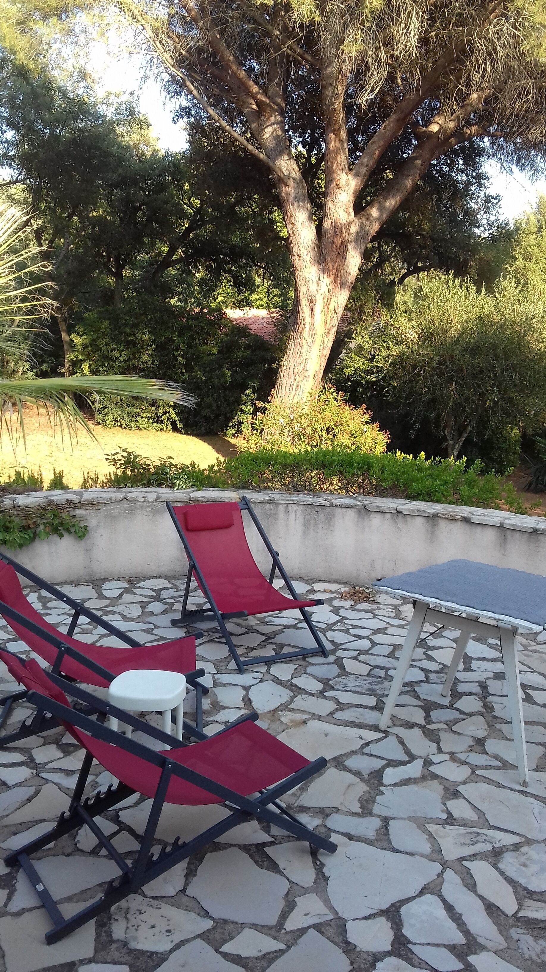 An outdoor seating area with stone flooring and red chairs.