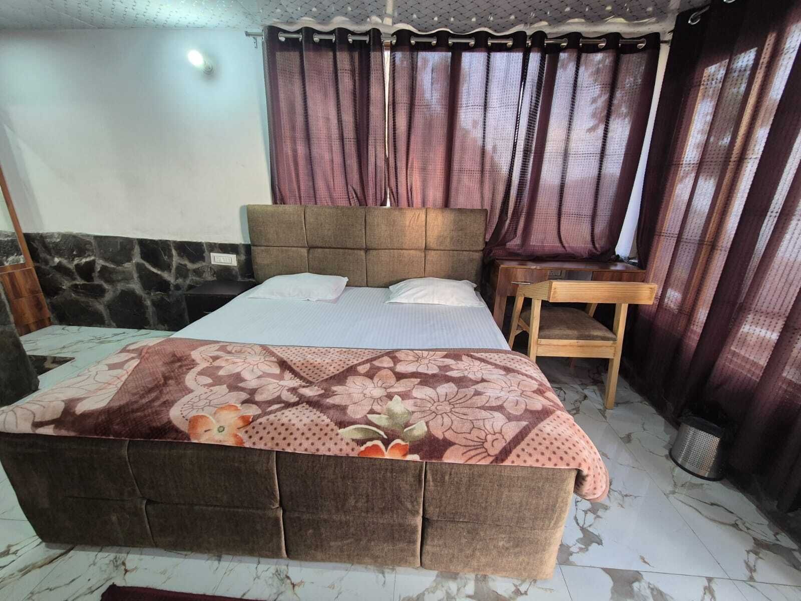 A bedroom with a bed, a wooden nightstand, a chair, and a window with curtains.