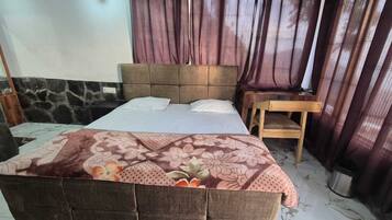 A bedroom with a bed, a wooden nightstand, a chair, and a window with curtains.