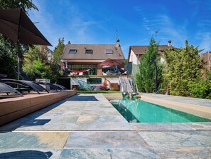 A pool area with lounge chairs, a hot tub, and a view of a house in the background. - Paris Garden River residence (Creteil)
