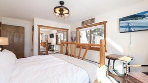 A bedroom with a large bed, a wooden headboard, a ceiling fan, a TV, and a window with a view of trees and mountains. - Private home on 5 acres - 5 min. from downtown Durango - Hot Tub/Game Room (Durango)