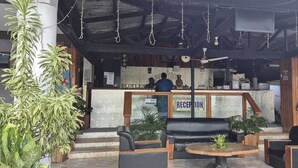 An outdoor seating area with a reception desk, chairs, and a table. - Bluelight Village Hotel (Nadi)