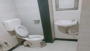 A bathroom with a toilet, a sink, and a mirror. - HOTEL Sai Leela Residency (Mumbai)