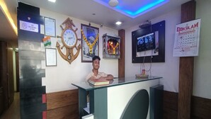 A reception area with a clock, calendar, and a television mounted on the wall. - HOTEL Sai Leela Residency (Mumbai)