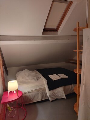 A small, cozy bedroom with a single bed, a bedside table with a lamp, and a wooden ladder. - Maison de ville quartier de France Vichy (Vichy)