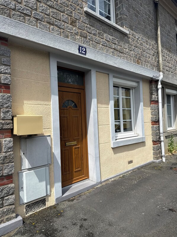 Un edificio de piedra de dos pisos con puerta principal de madera, una ventana pequeña y un cartel con el número 12.